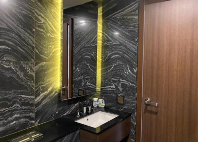 Modern bathroom with marble walls and illuminated mirror