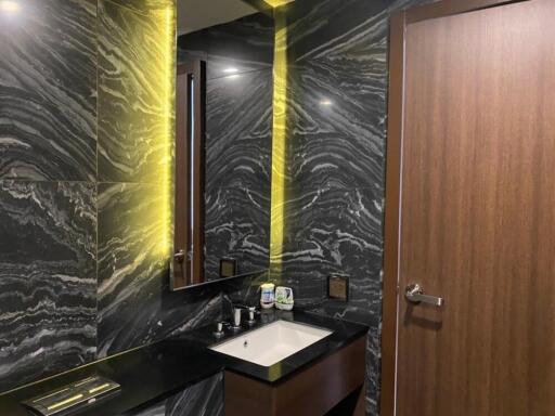 Modern bathroom with marble walls and illuminated mirror