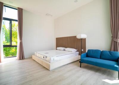 Modern bedroom with large window, bed, and blue sofa