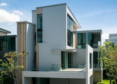 Modern multi-story residential building with large windows and surrounding greenery