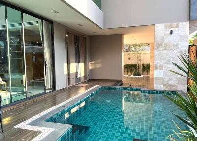 Modern outdoor pool area with adjacent covered patio and large windows