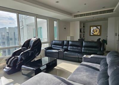 Modern living room with large windows, leather seating, and massage chair