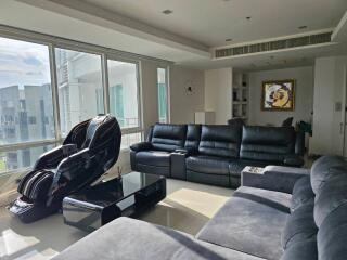 Modern living room with large windows, leather seating, and massage chair