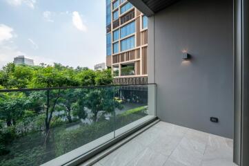 Balcony with glass railing and view of greenery