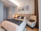 Modern bedroom with beige and gray tones, cozy armchair, and decorative framed artwork