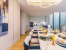 Modern dining area with table set for a meal, view of a kitchen in the background