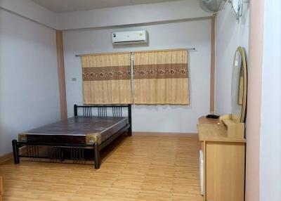 Spacious minimalist bedroom with bed, desk, air conditioner, and window