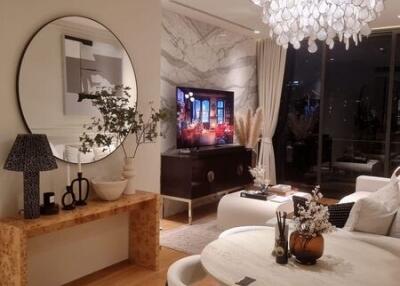 Modern living room with a dining area, chandelier, and wall-mounted TV