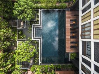 Top view of a swimming pool in a landscaped outdoor area surrounded by greenery and seating areas