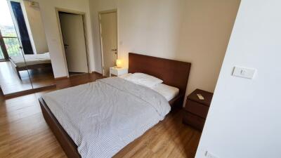 Bedroom with wooden floor, bed, bedside table, and mirrored wardrobe