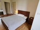 Bedroom with wooden floor, bed, bedside table, and mirrored wardrobe