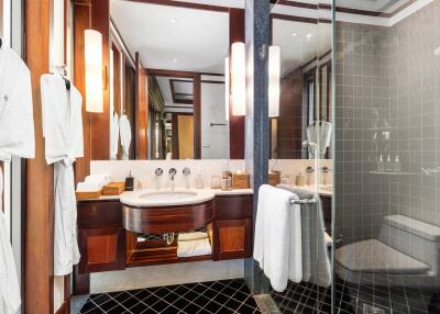 Modern bathroom with a glass shower, vanity sink, and robe hangers