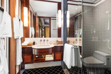 Modern bathroom with a glass shower, vanity sink, and robe hangers