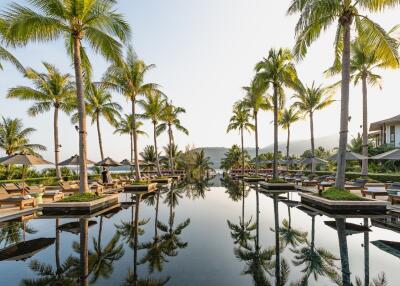 Luxurious outdoor pool area with palm trees and loungers