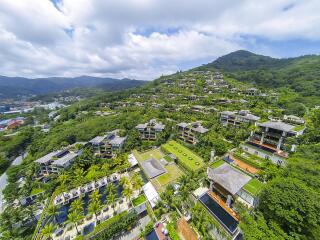 Aerial view of a tropical luxury villa complex on a hillside surrounded by greenery