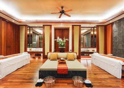 Luxury spa room with wooden flooring, massage tables, and ambient lighting