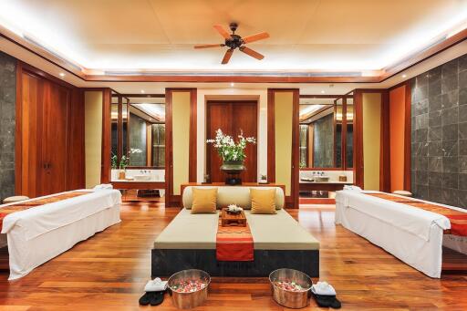 Luxury spa room with wooden flooring, massage tables, and ambient lighting