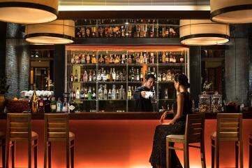 Modern, elegant bar area with various liquors and stylish seating