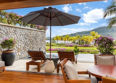 Beautifully designed outdoor patio with lounge chairs, large umbrella, and scenic view
