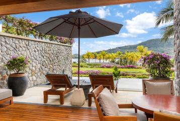 Beautifully designed outdoor patio with lounge chairs, large umbrella, and scenic view