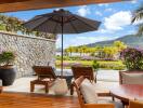 Beautifully designed outdoor patio with lounge chairs, large umbrella, and scenic view