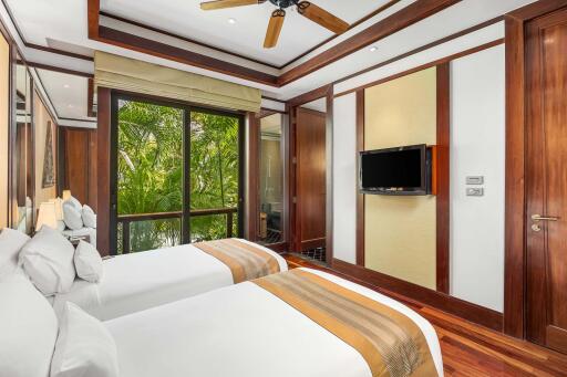 Bedroom with twin beds, wooden accents, and a large window with garden view