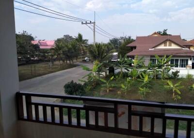 View from outdoor balcony overlooking neighborhood street with houses, trees, and power lines