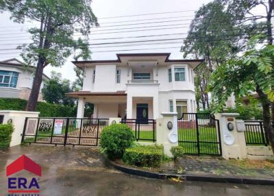 Beautiful two-story house with a gated garden and walkway, surrounded by greenery