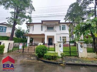 Beautiful two-story house with a gated garden and walkway, surrounded by greenery