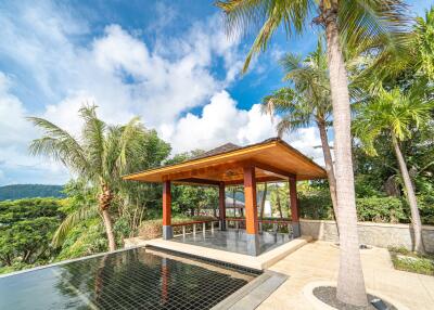 Outdoor pavilion with surrounding tropical trees and a reflective water feature
