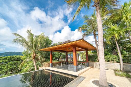 Outdoor pavilion with surrounding tropical trees and a reflective water feature