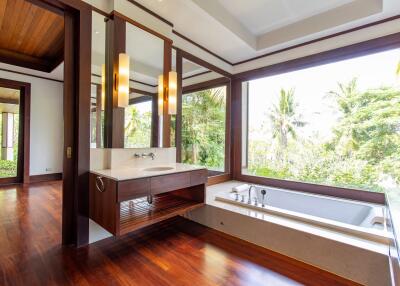 Spacious bathroom with large windows overlooking greenery