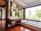 Spacious bathroom with large windows overlooking greenery