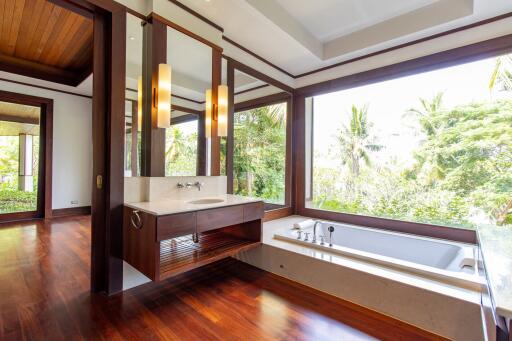 Spacious bathroom with large windows overlooking greenery