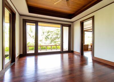 Spacious living room with wooden ceiling and floor, large windows, and outdoor view