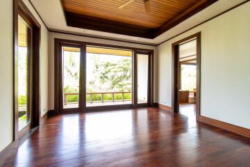 Spacious living room with wooden ceiling and floor, large windows, and outdoor view