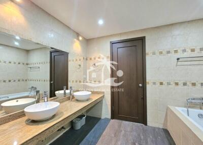 Modern bathroom with double sinks, bathtub, and large mirror