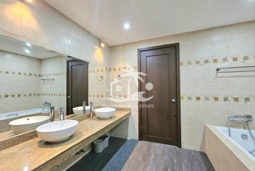 Modern bathroom with double sinks, bathtub, and large mirror