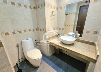 Modern bathroom with a toilet, sink, and vanity mirror