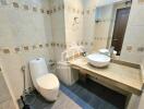 Modern bathroom with a toilet, sink, and vanity mirror