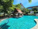 Outdoor swimming pool with a traditional pavilion and surrounding greenery