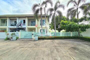 Exterior view of a modern house with a gated yard and palm trees