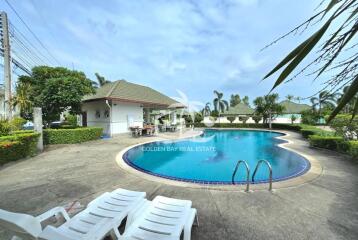 Outdoor pool with lounge chairs and greenery