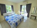 Bright bedroom with large windows and blue floral bedding