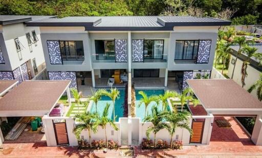 Exterior view of a modern two-story duplex with a swimming pool and covered parking spaces