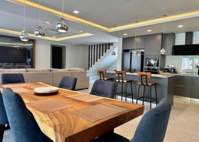 Modern open concept living room and kitchen area with dining table and staircase