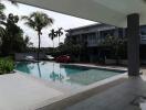 Outdoor pool area with parked cars and residential building