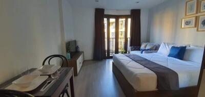 Spacious bedroom with a large bed, balcony access, and dining area