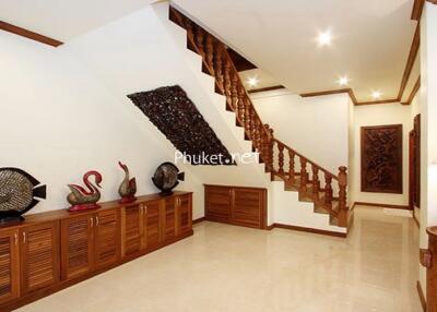 Well-lit hallway with wooden staircase and decorative items