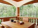 Wood-furnished balcony with outdoor dining table set overlooking greenery